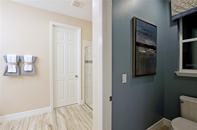 bathroom featuring an enclosed shower, a textured ceiling, wood-type flooring, and toilet