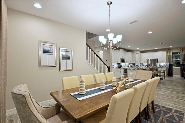 dining space with an inviting chandelier and light hardwood / wood-style flooring