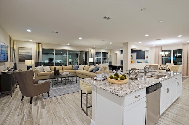 kitchen featuring sink, white cabinetry, a kitchen island with sink, light stone countertops, and stainless steel dishwasher