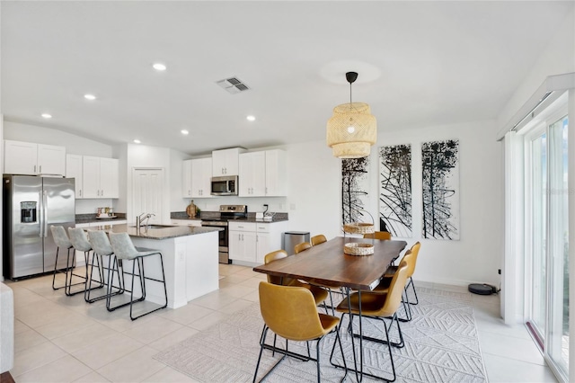 tiled dining room with lofted ceiling and sink