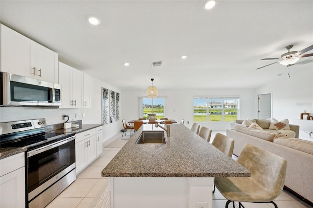 kitchen featuring a center island with sink, a kitchen breakfast bar, white cabinets, sink, and stainless steel appliances