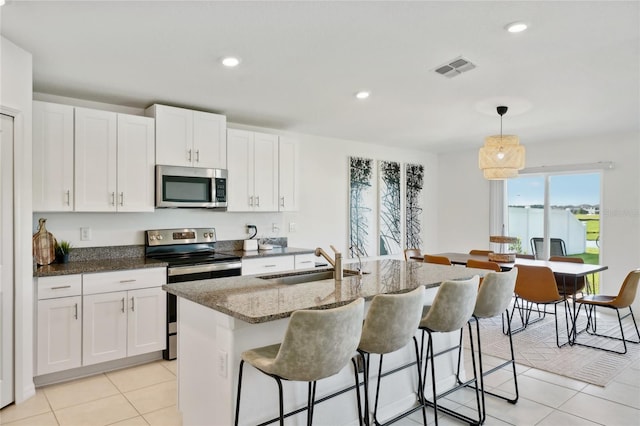 kitchen with a kitchen island with sink, white cabinetry, sink, and appliances with stainless steel finishes