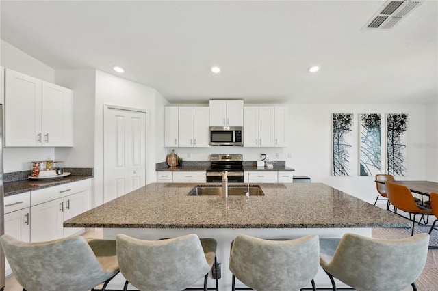 kitchen with a center island with sink, a kitchen bar, white cabinetry, and stainless steel appliances