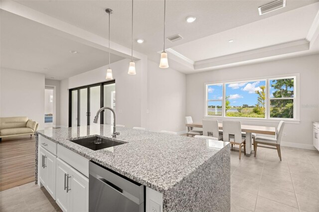 kitchen featuring light stone counters, white cabinetry, decorative light fixtures, sink, and dishwasher