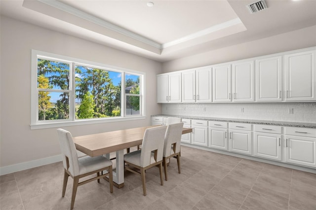 dining space with a raised ceiling, visible vents, crown molding, and baseboards