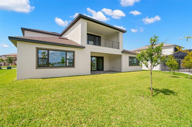 rear view of property with a lawn and a balcony