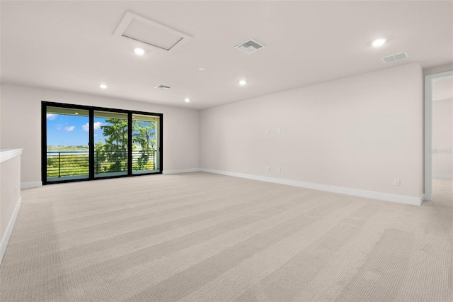 empty room with baseboards, attic access, visible vents, and light colored carpet