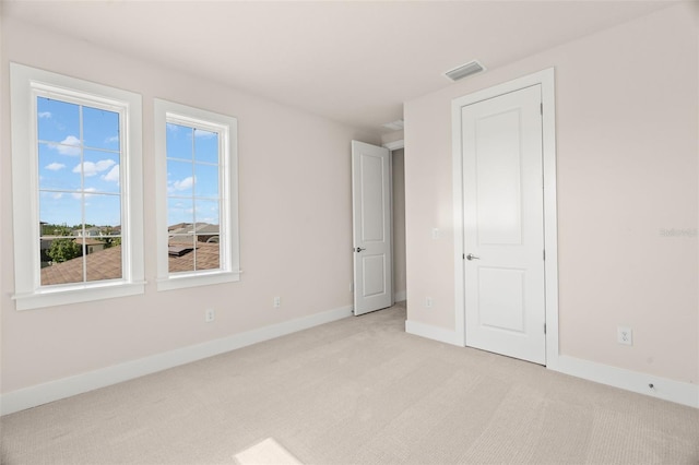 unfurnished bedroom featuring baseboards, visible vents, and light colored carpet