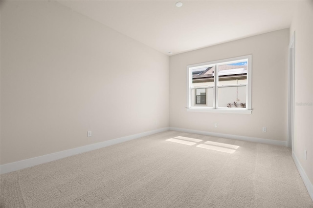 empty room featuring carpet and baseboards