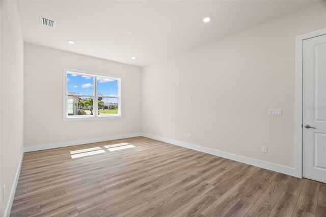 spare room with light wood finished floors, baseboards, and visible vents