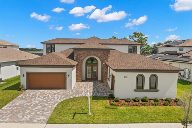 view of front of property with french doors, roof with shingles, decorative driveway, a front yard, and a garage