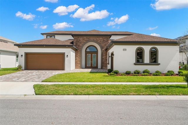 mediterranean / spanish-style house with an attached garage, stucco siding, decorative driveway, and french doors