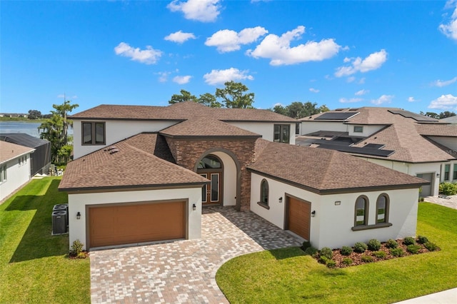 view of front of home featuring a garage, a front yard, decorative driveway, and a shingled roof