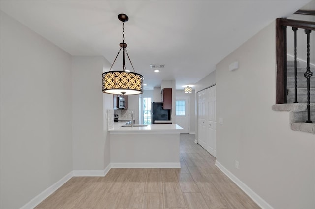 kitchen featuring appliances with stainless steel finishes, kitchen peninsula, sink, and backsplash