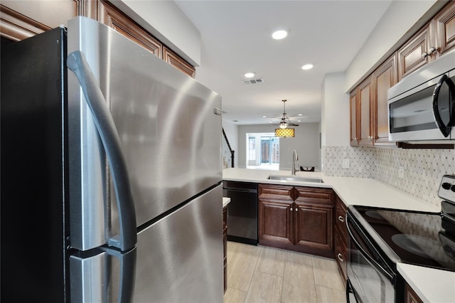 kitchen featuring sink, stainless steel appliances, tasteful backsplash, decorative light fixtures, and light wood-type flooring