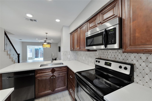 kitchen featuring pendant lighting, tasteful backsplash, sink, kitchen peninsula, and stainless steel appliances