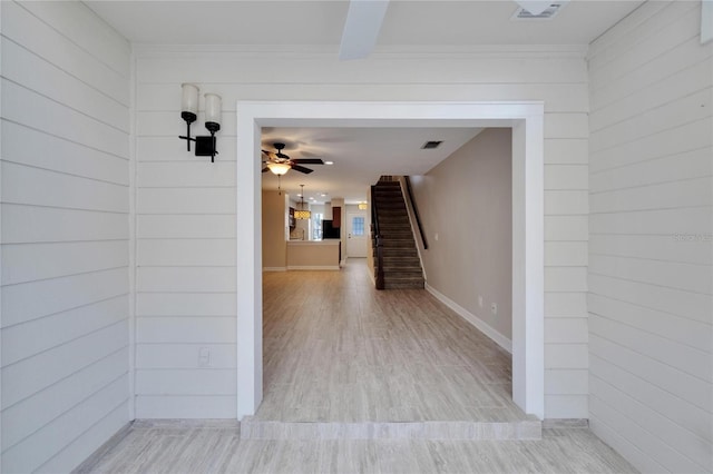 corridor with wood walls and light hardwood / wood-style flooring