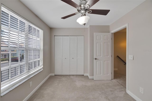 unfurnished bedroom featuring light carpet, a closet, and ceiling fan