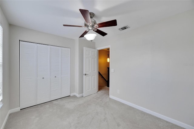 unfurnished bedroom featuring ceiling fan, a closet, and light carpet