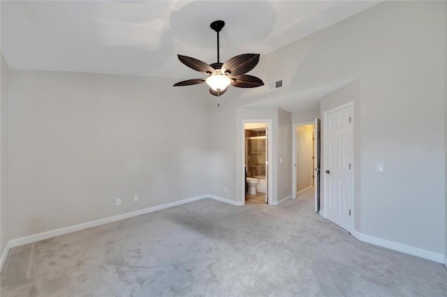 unfurnished bedroom featuring ceiling fan, light carpet, and ensuite bath