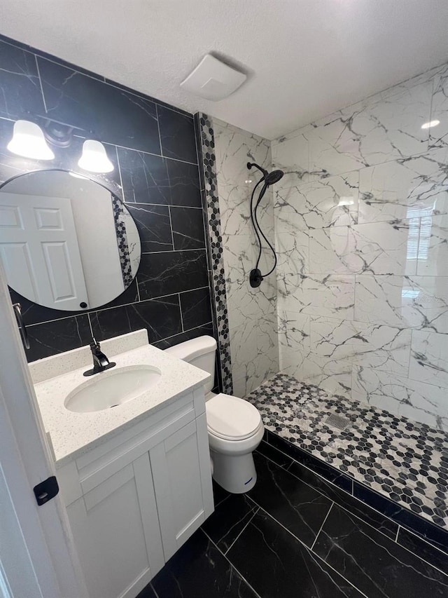 bathroom with tile walls, vanity, tiled shower, toilet, and a textured ceiling