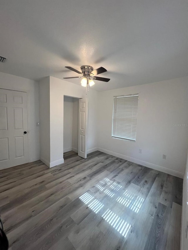 unfurnished bedroom featuring hardwood / wood-style flooring, ceiling fan, and a closet