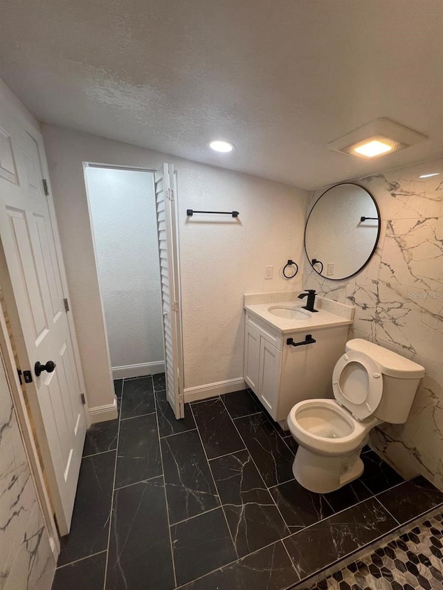 bathroom featuring vanity, toilet, and a textured ceiling