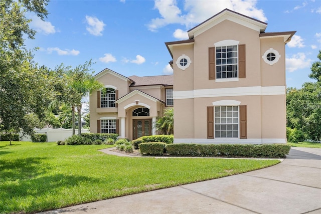 mediterranean / spanish home with a front yard, fence, and stucco siding