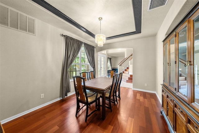 dining room featuring a chandelier, dark wood finished floors, a raised ceiling, and visible vents