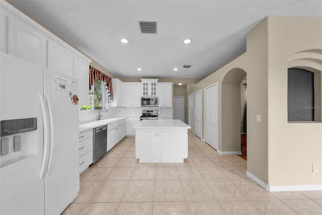 kitchen featuring light countertops, appliances with stainless steel finishes, glass insert cabinets, white cabinetry, and a kitchen island