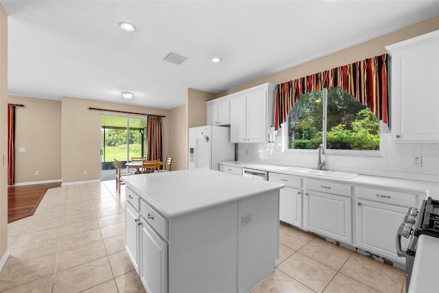 kitchen with a kitchen island, white refrigerator with ice dispenser, white cabinetry, and a sink