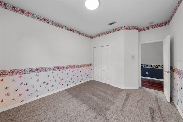 spare room featuring baseboards, visible vents, carpet flooring, and wallpapered walls