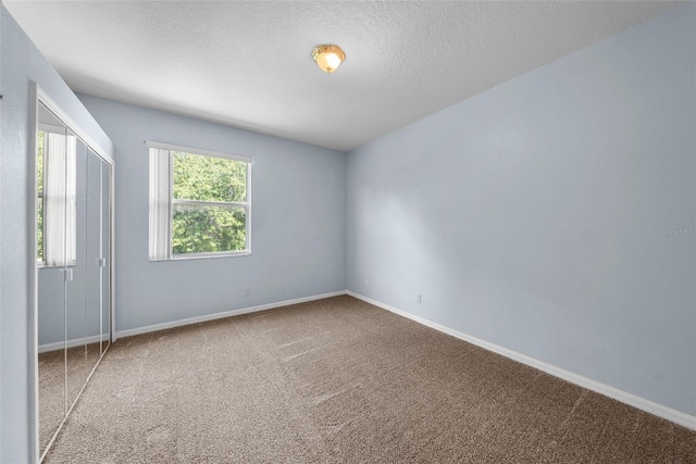 spare room featuring carpet floors, baseboards, and a textured ceiling