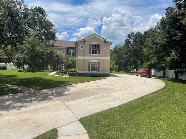 exterior space featuring fence, a front lawn, and stucco siding