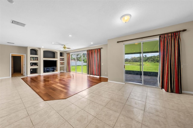 unfurnished living room featuring light tile patterned floors, built in shelves, visible vents, and baseboards