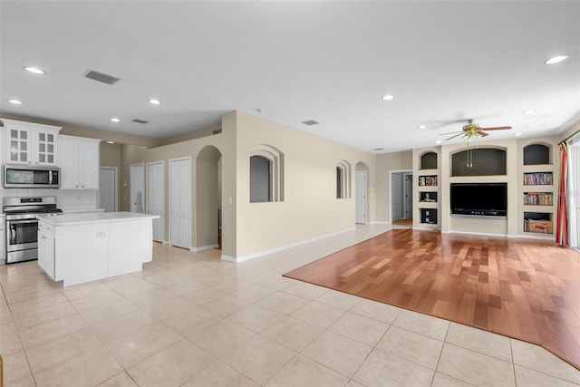 kitchen featuring visible vents, appliances with stainless steel finishes, open floor plan, light countertops, and white cabinetry