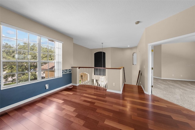 unfurnished room with a textured ceiling, baseboards, and wood finished floors