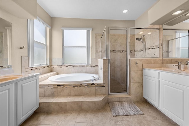 full bath with a bath, a shower stall, two vanities, and a sink