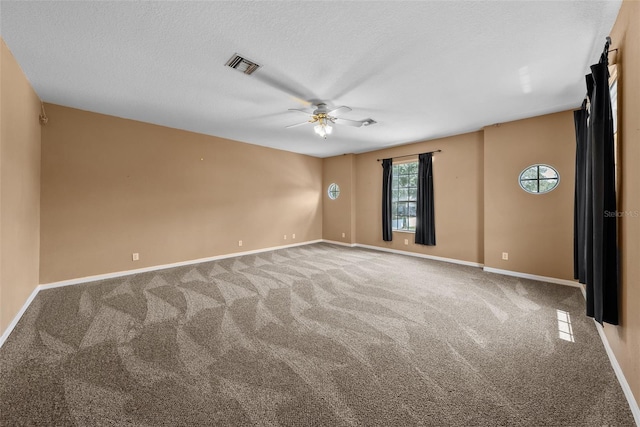 carpeted empty room featuring a textured ceiling, baseboards, visible vents, and a ceiling fan