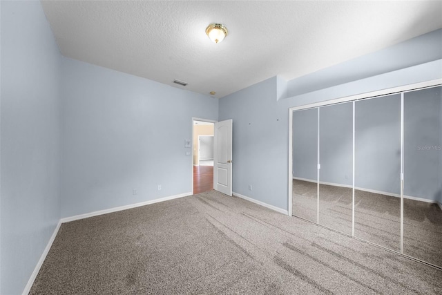 unfurnished bedroom featuring carpet, baseboards, visible vents, and a textured ceiling