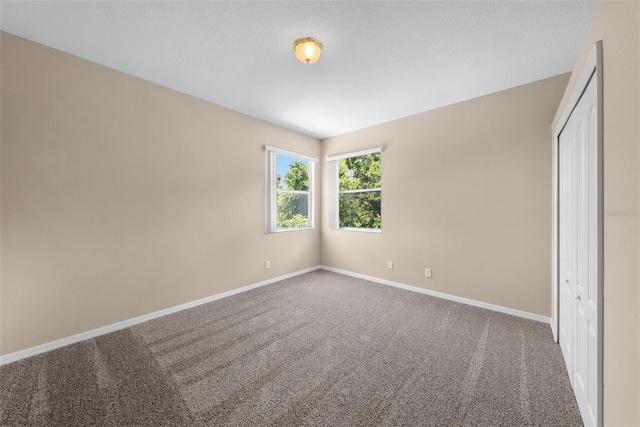 unfurnished bedroom with carpet floors, a closet, and baseboards