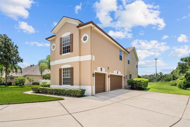 view of front of property with a garage, a front yard, concrete driveway, and stucco siding