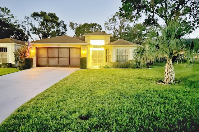 view of front facade with stucco siding, driveway, a garage, and a front lawn