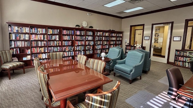 sitting room featuring wall of books, crown molding, and carpet floors