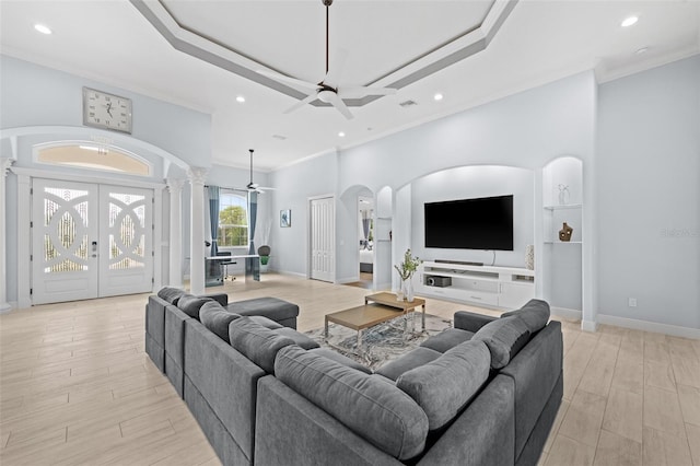 living room with ceiling fan, ornamental molding, and a raised ceiling