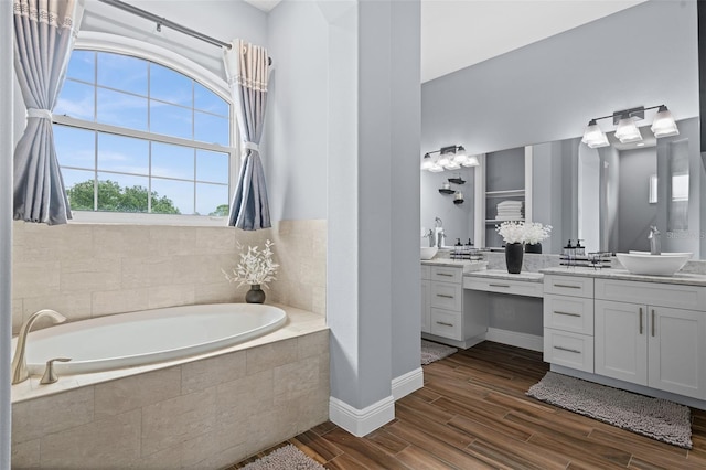 bathroom with vanity and tiled tub