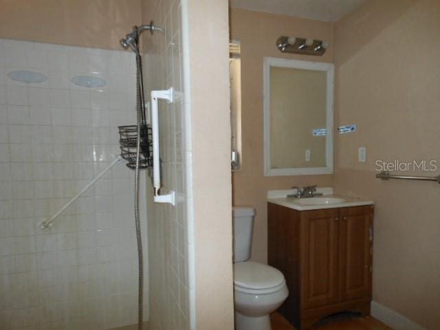 bathroom with vanity, a tile shower, and toilet