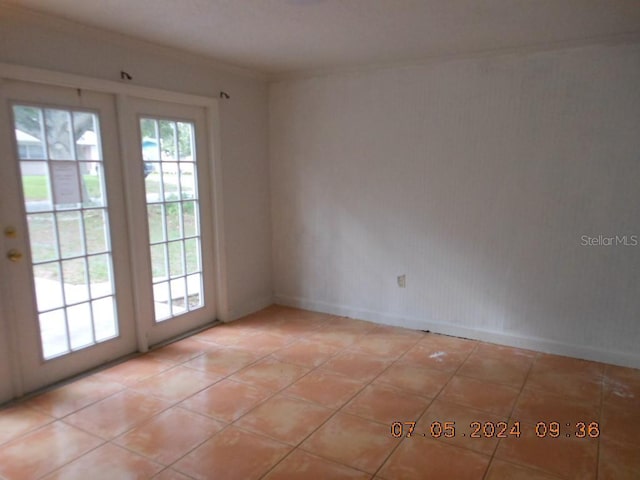 unfurnished room featuring a healthy amount of sunlight, crown molding, baseboards, and light tile patterned floors