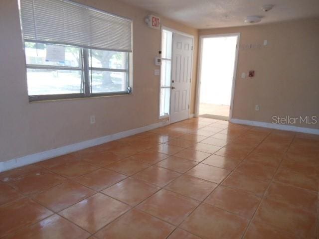 tiled empty room featuring baseboards