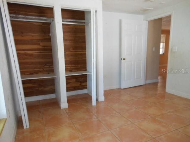 interior space featuring baseboards, light tile patterned flooring, and multiple closets